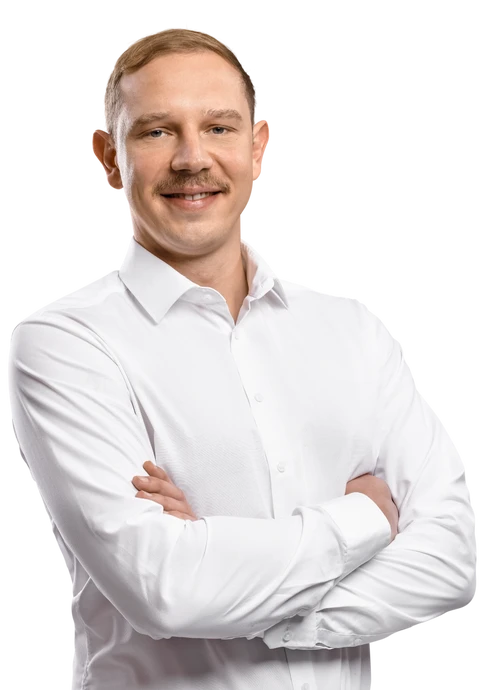 Mann in weißem Hemd mit verschränkten Armen, frontal blickend und leicht lächelnd.