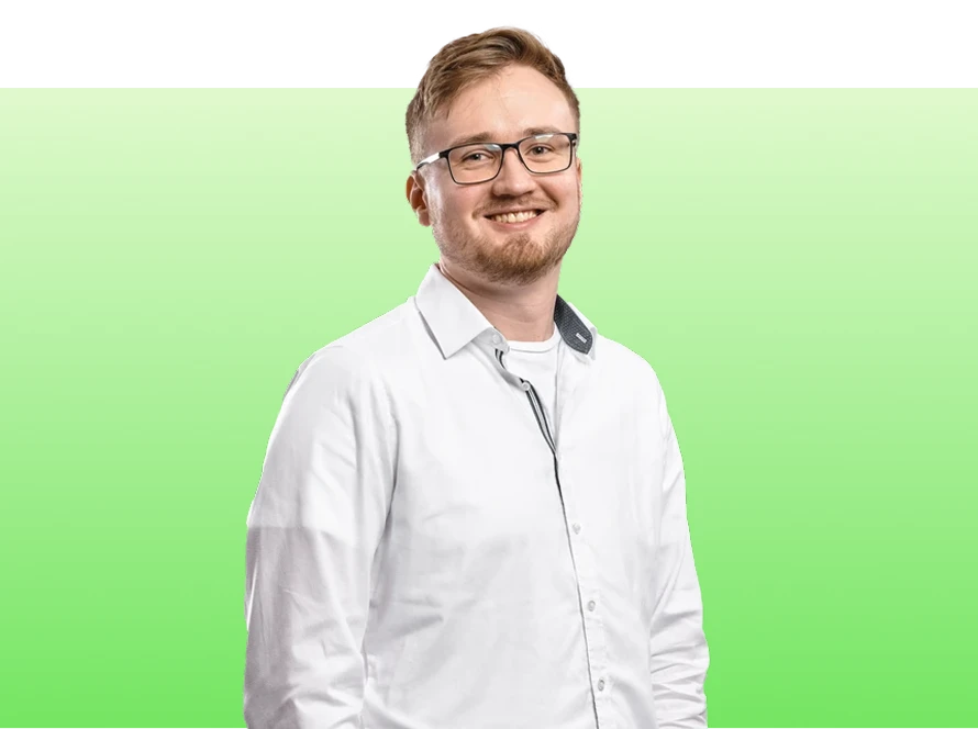 Ein Mann mit Brille, weißem Hemd, kurzem Bart, lächelnd, vor grünem Farbverlauf.