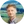 Mann mit hellem Haar, grauer Jacke und hellem Hemd vor grünen Feldern und blauem Himmel.